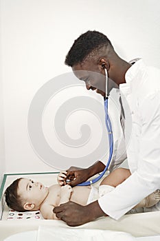 African doctor examines a little boy on couch