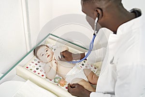 African doctor examines a little boy on couch