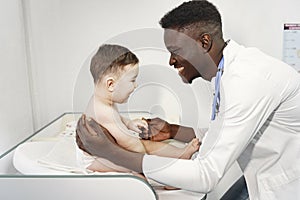 African doctor examines a little boy on couch