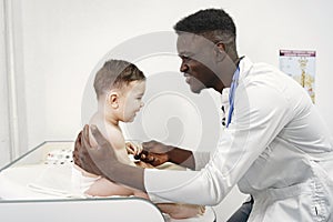 African doctor examines a little boy on couch