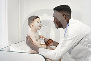 African doctor examines a little boy on couch
