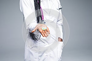 African doctor holding pills close up isolated on gray background