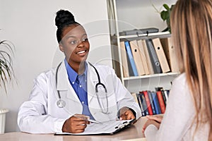 African doctor physician consulting caucasian woman patient at medical visit.