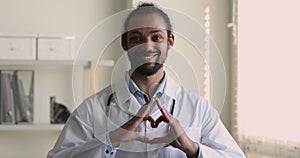 African doctor showing heart with fingers smile looks at camera