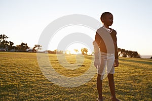 African elementary school girl standing in a park at sunset