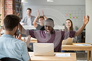 African employee excited about online win, coworking team congra