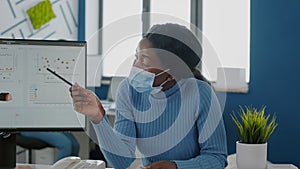 African employee with face mask explaning project to invalid coworker