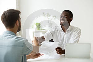 African employer handshaking new hire caucasian employee holding photo