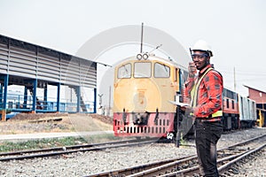 African engineer   control a the train on railway with talking by radio communication or walkie talkie