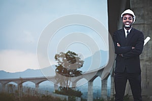 African engineer man or architect checking construction with white safety helmet in construction site. Standing at highway