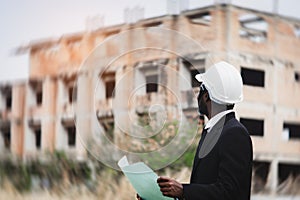 African engineer manager checking blueprint for demolition construction plan and rebuild at the site