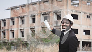 African engineer manager holding and checking blueprint for demolition construction plan and rebuild at the site