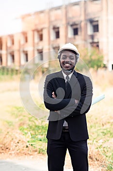 African engineering man stand up and holding tablet with building background