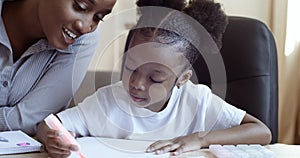 African ethnic mom teaching helping learning distance daughter child to do homework. American family spending happy time