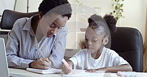 African ethnic mom teaching helping learning distance daughter child to do homework. American family spending happy time
