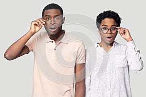 Confused african couple gawp at camera open mouth lowering glasses photo