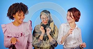 African, European and Muslim dance together isolated on a blue background. Internationality, cute, friendship between