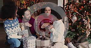 African family chatting together near Christmas tree with gifts