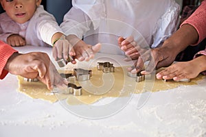 African family hands cutting cookie shapes in a cookie dough in the kitchen.