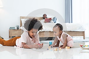 African family, little boy and cute toddler baby girl, brother and sister have fun playing model toys and wooden blocks together