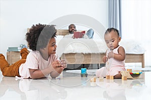 African family, little boy and cute toddler baby girl, brother and sister have fun playing model toys and wooden blocks together