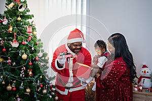 African family, Nigerian father wearing a red Santa costume open gift box for a 4-month-old son