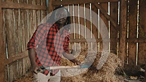 African farmer lifting hay indoors