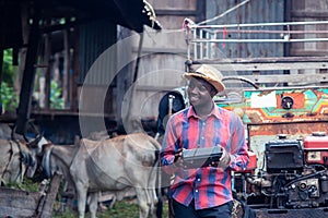 African farmer man with retro radio broadcast receiver on shoulder stands happy smiling outdoor on old cow stall background