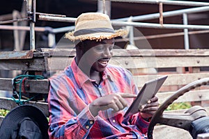 African farmer man using tablet with happy and smiling  on old tractor