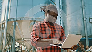 African farmer using laptop in front of the silo storage system