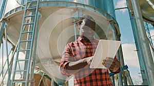 African farmer using laptop in front of the silo storage system