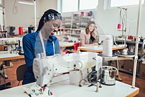 African fashion designer using sewing machine in her workshop