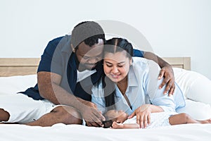 African father and Asian mother touching and lull cute newborn baby sleeping lying on bed, smiling looking at innocent infant with