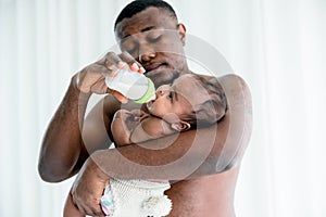 African father feeding milk from bottle milk to his baby newborn daughter