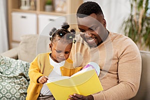 African father reading book for baby daughter