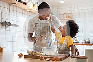 African Father and son enjoying during bake cookies at home together photo
