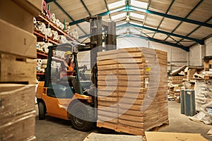 African female forklift operator moving boxes around a warehouse