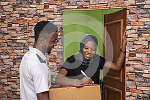 African female signing a proof of delivery while receiving a parcel from the courier