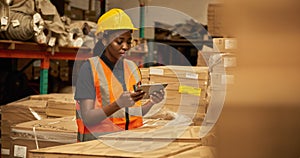 African female warehouse worker using a tablet to check stock in boxes