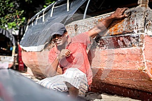 African fisherman on beach repairing boat