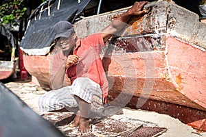 African fisherman on beach repairing boat