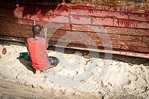 African fisherman on beach repairing boat