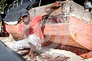 Pescatore sul Spiaggia riparazione una barca 