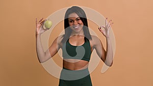 African Fitness Woman Posing With Apple Gesturing Okay, Beige Background