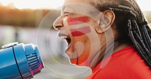 African football fan with painted face and megaphone cheering for her team