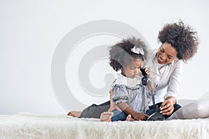 African full family sit on bed in living room play with little kids parents tickles children daughter happy time