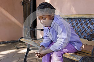 african girl with braids sited on the bench in front of the house