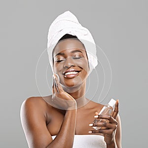 African girl cleaning skin with cotton pads and face toner after bath