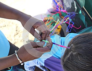 African girl hand making a piggy bank in the girl`s hair on the