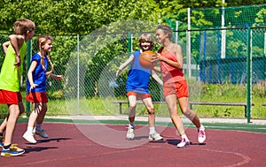 African girl holds ball and teens play basketball